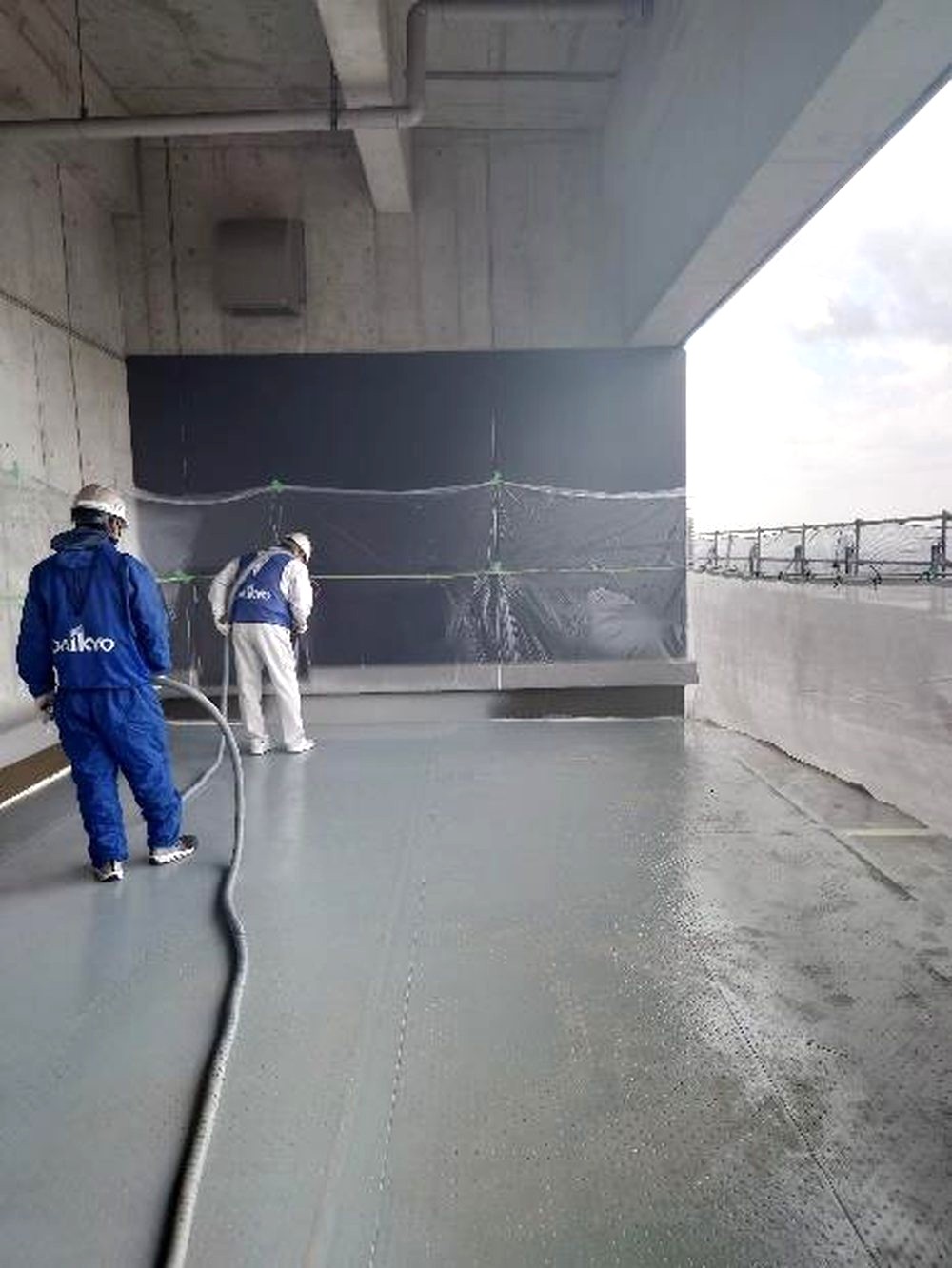 屋上にポリウレアを吹き付ける施工の様子